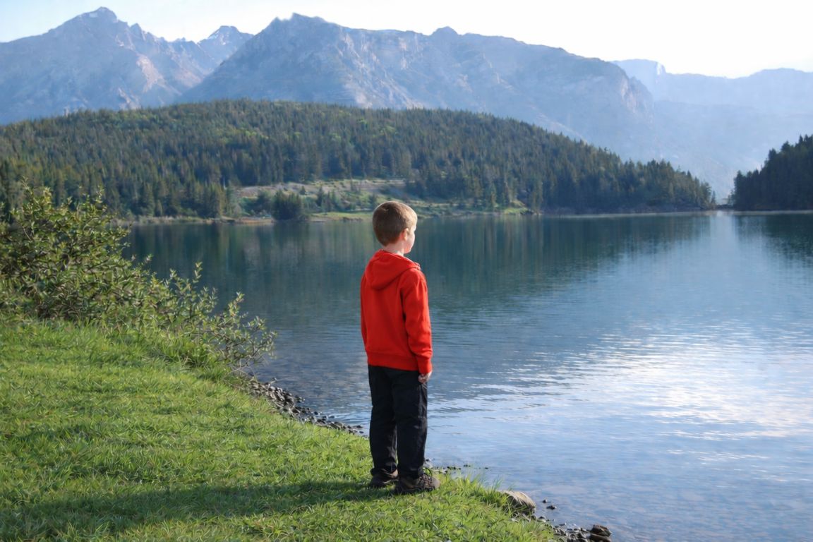 Child standing by Two Jack Lake shoreline with Rocky Mountain views during a Banff National Park Tours excursion